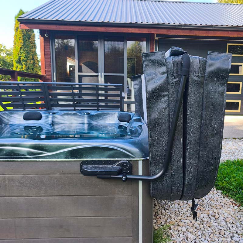 Basseini kattetõstuk ALifter I5 | Santeco Kotikylpylä Above ground hot tub with a folded black cover hung over its side in a residential yard